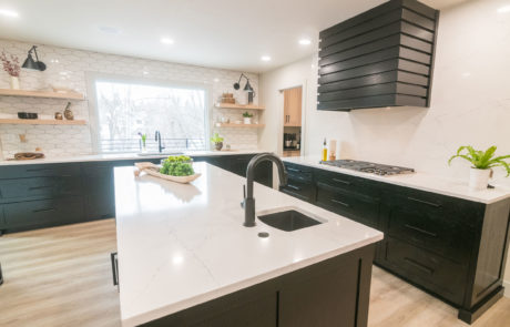 Wide view of kitchen with white and black island